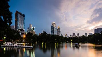 A city skyline at dusk with illuminated buildings reflecting on a calm river.