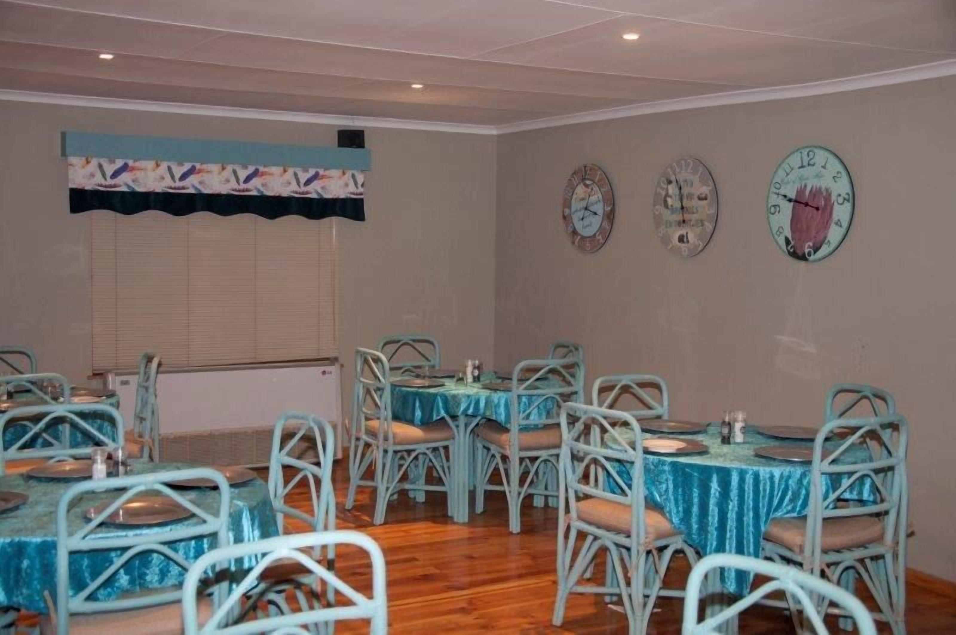 A dining area with round tables and chairs, a window with blinds, and three wall clocks.