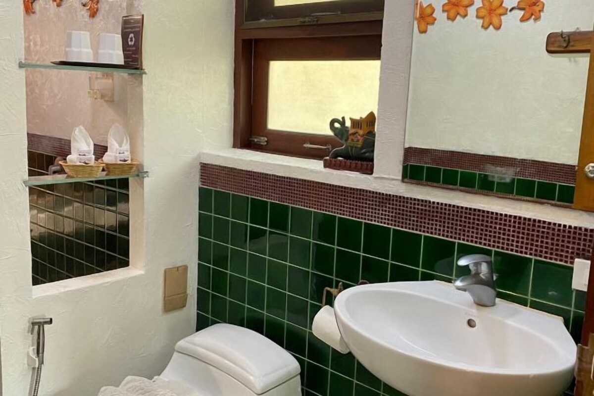 A bathroom with a toilet, sink, and window.