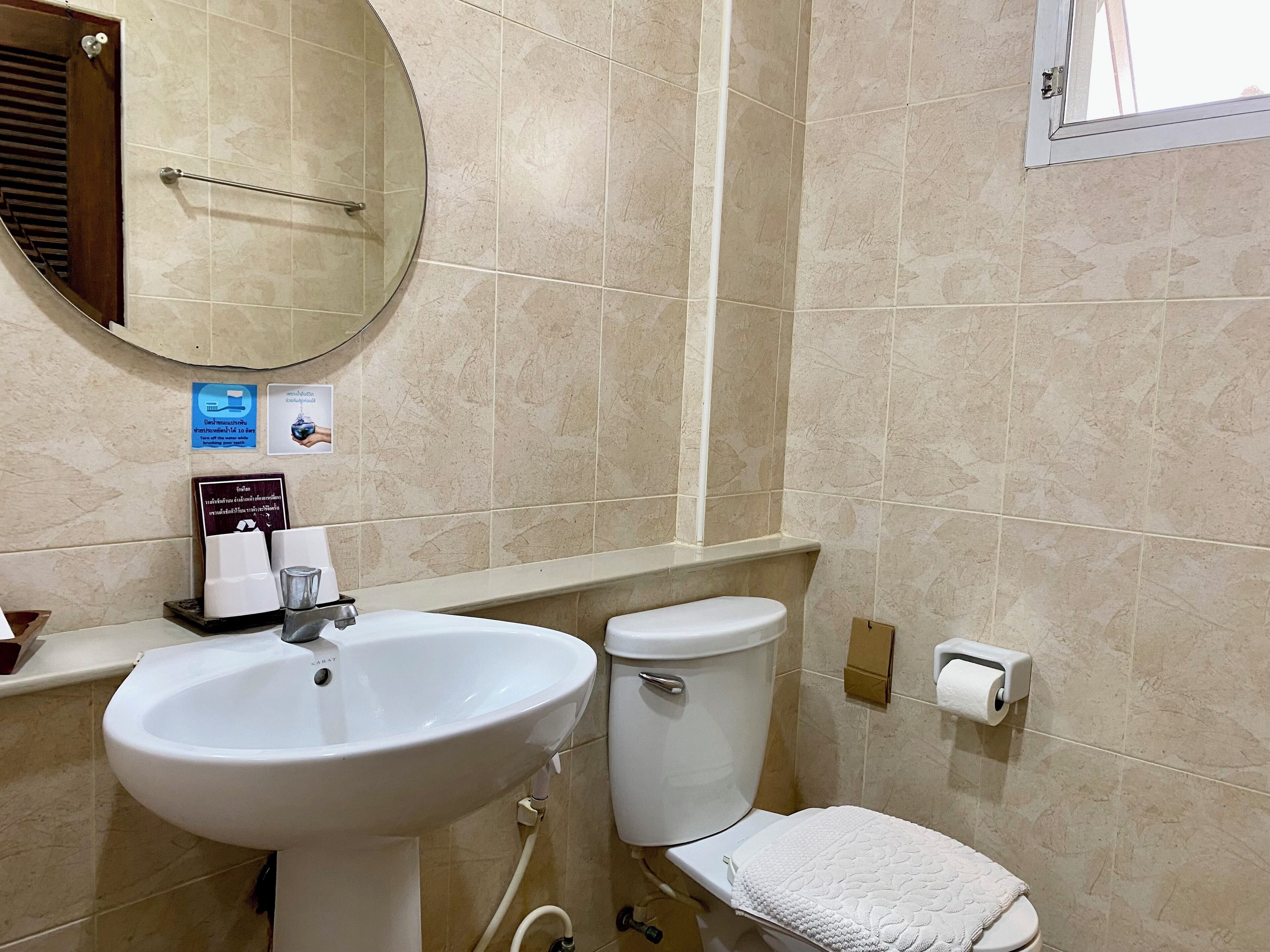 Une salle de bain avec un lavabo, des toilettes et un miroir. Il y a des panneaux sur le mur et un porte-serviettes.