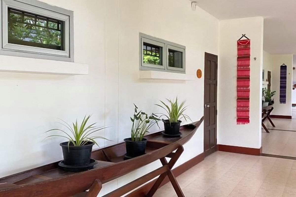 A hallway with a wooden bench, potted plants, and a red decorative item on the wall.