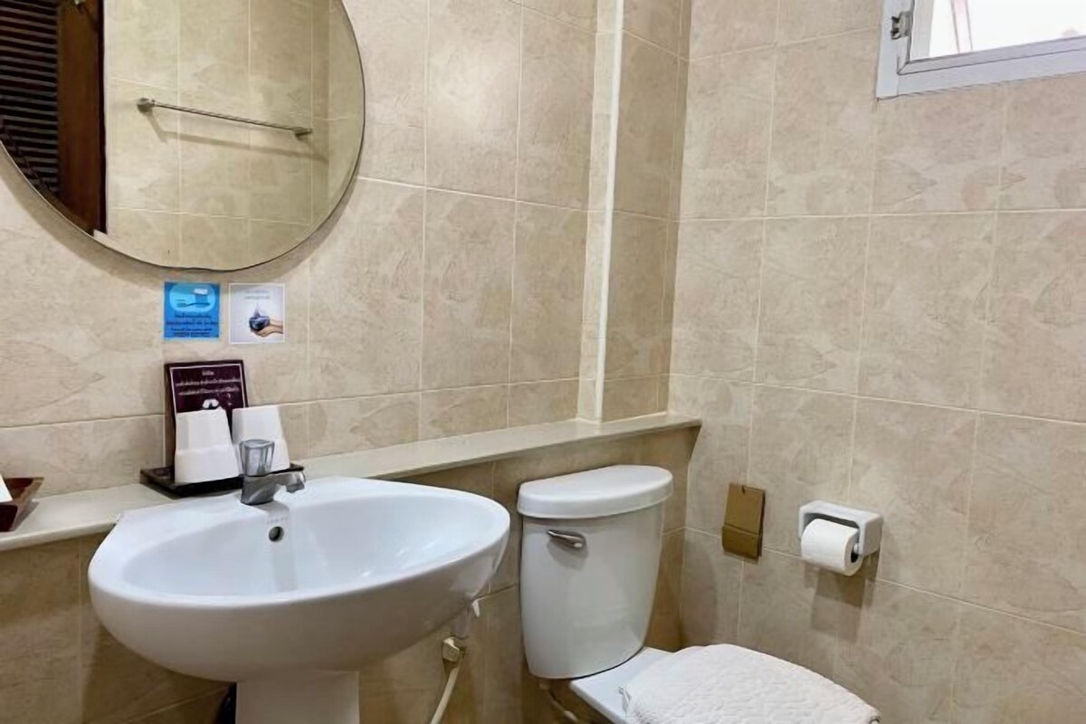 A bathroom with a round mirror, a sink, a toilet, and a towel rack.