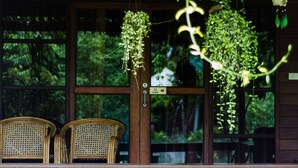 A wooden porch with two wicker chairs and hanging plants. - Maikaew Damnoen Resort (Damnoen Saduak)