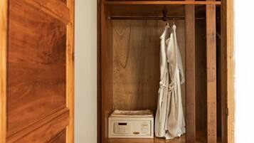 A wooden wardrobe with a hanging rack and a microwave inside.