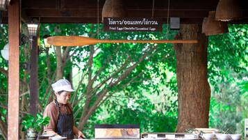 A restaurant with a wooden counter, a sign indicating menu items, and a potted plant.