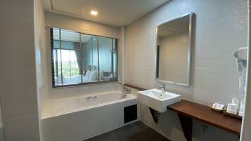Un baño moderno con bañera, lavamanos y un espejo grande.