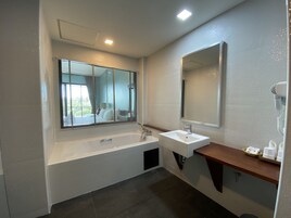 Un baño moderno con bañera, lavamanos y un espejo grande.