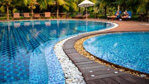 A swimming pool with a tiled edge, surrounded by palm trees and lounge chairs. - Maikaew Damnoen Resort (Damnoen Saduak)