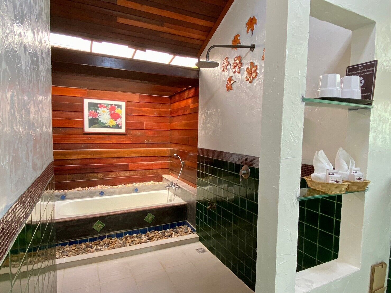 A bathroom with a wooden wall, a bathtub, a shower, and a shelf with toiletries.