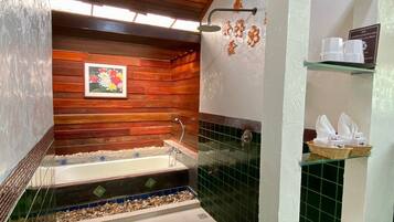 A bathroom with a wooden wall, a bathtub, a shower, and a shelf with toiletries.
