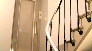 A staircase with wooden steps and black balusters, leading to a door with a handle.