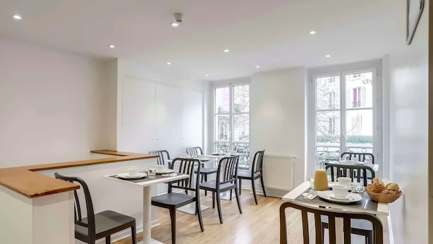 A modern dining area with a long table, chairs, and a view of the city.