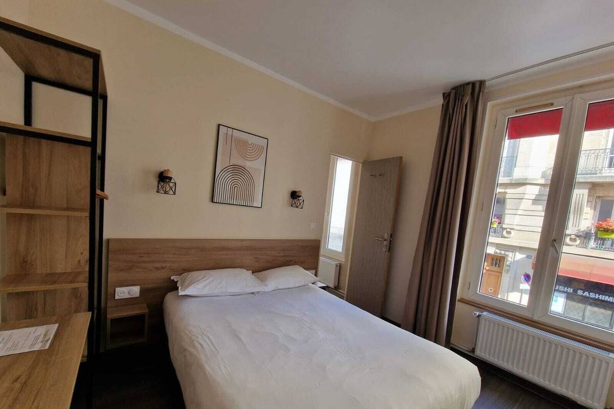 Une chambre d’hôtel avec un lit, un bureau et une fenêtre avec des rideaux.