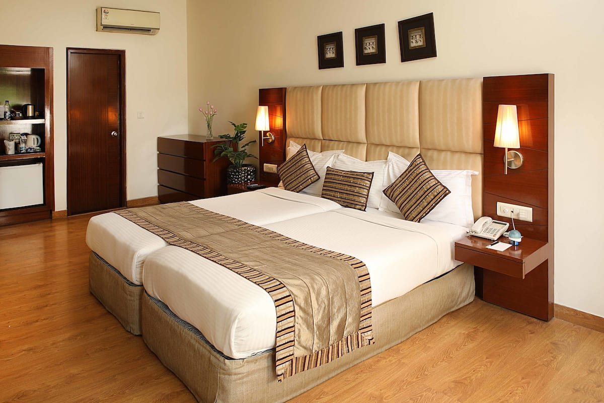 A hotel room with a large bed, bedside tables, a desk, and a wardrobe.