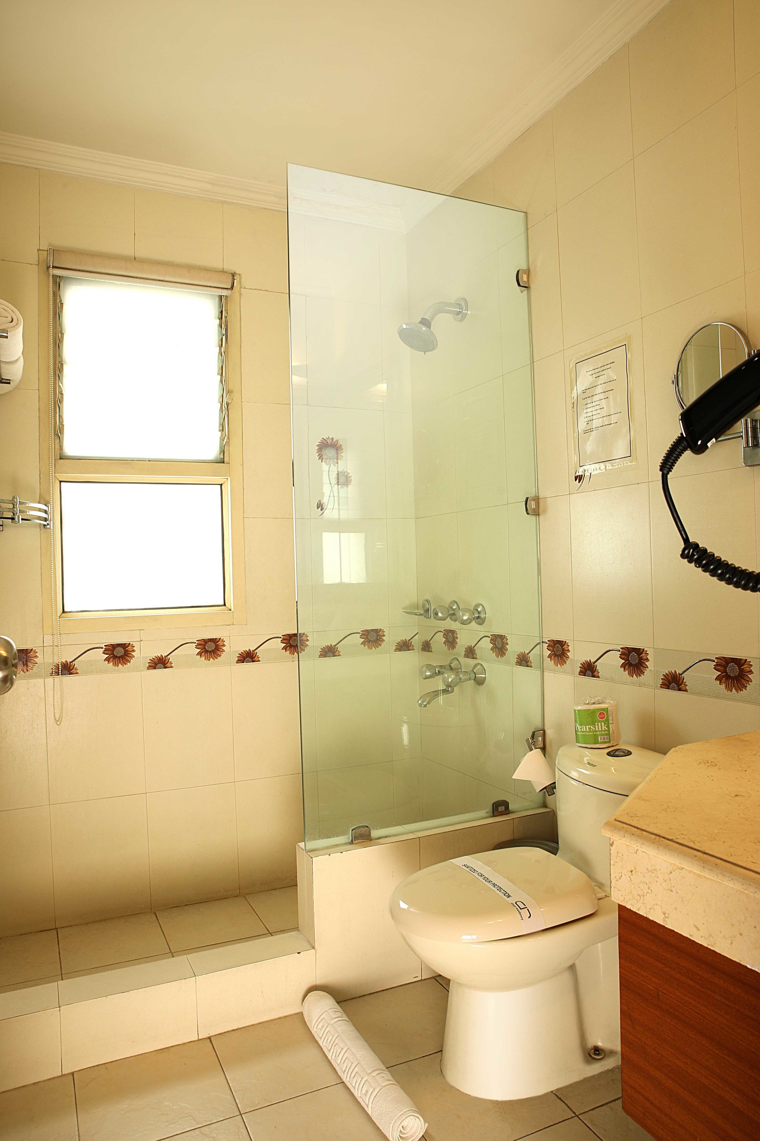 Een badkamer met toilet, een douchecabine en een raam.