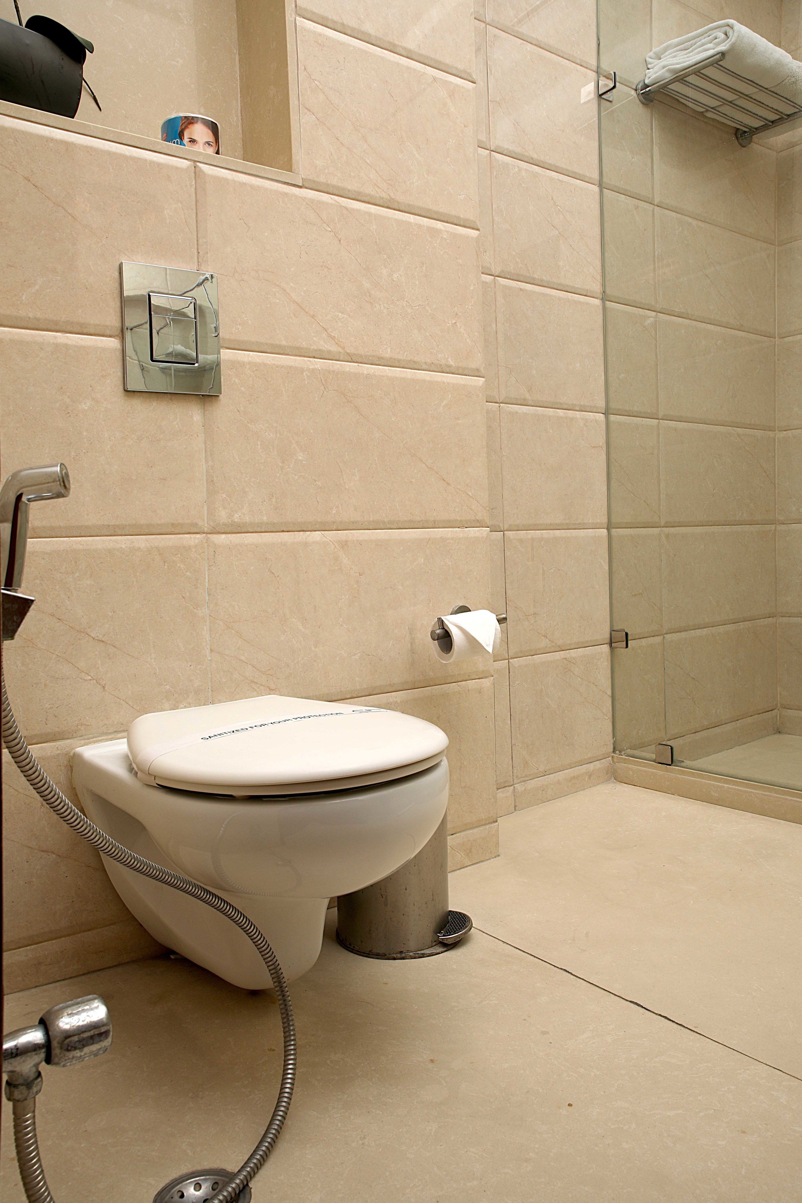 A bathroom with a toilet, a glass shower enclosure, and a towel rack.