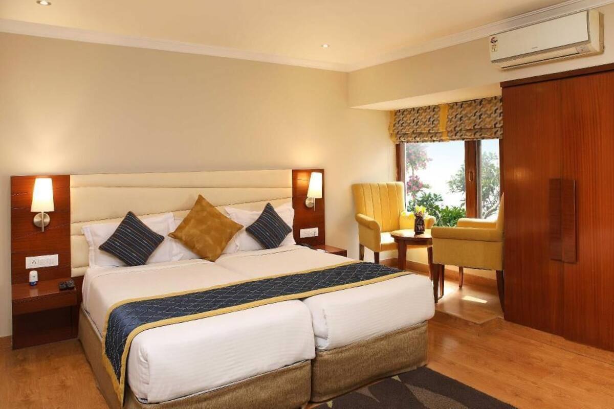A hotel room with a large bed, bedside tables, a chair, a desk, and a wardrobe.