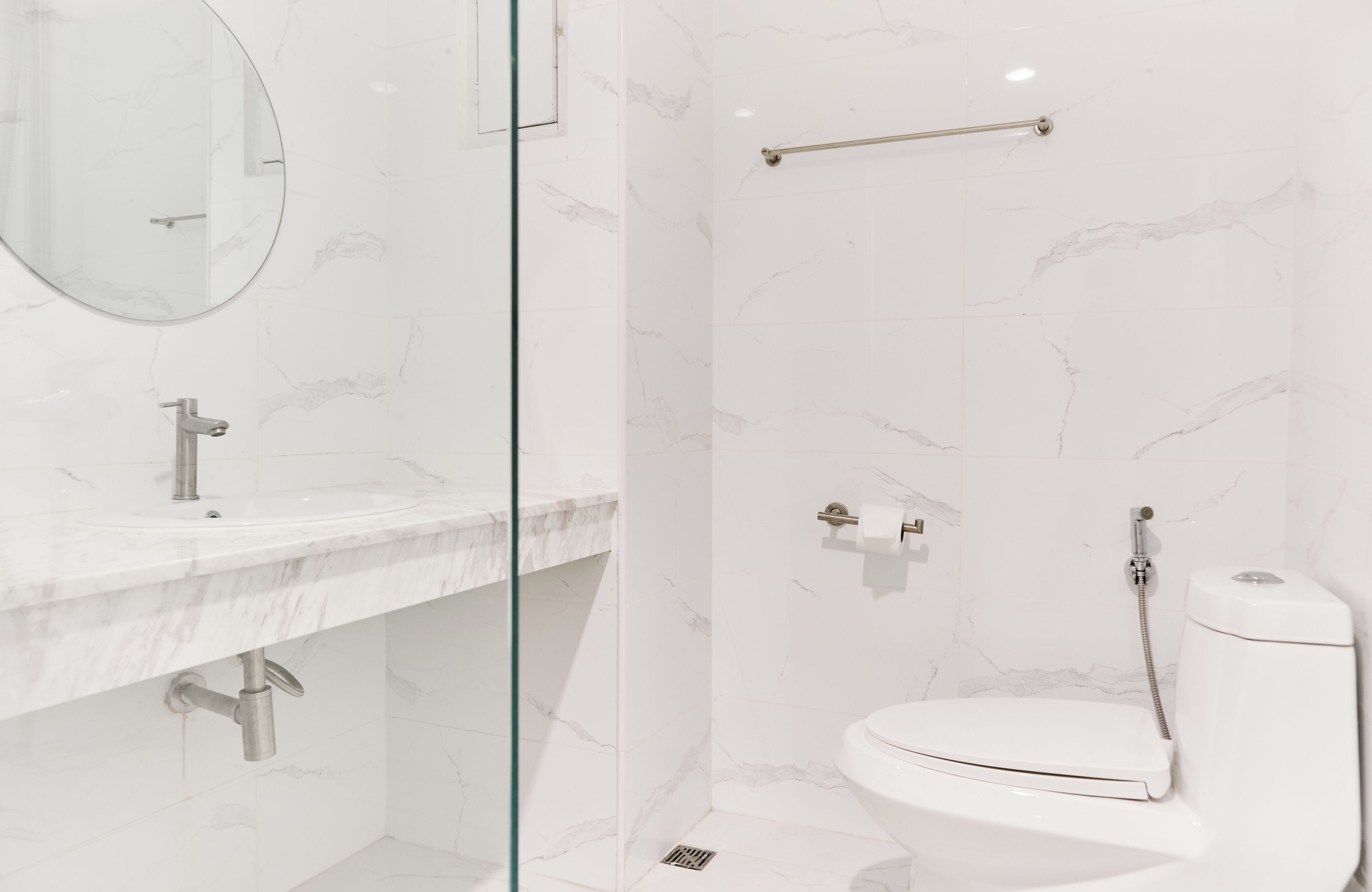 Une salle de bain moderne avec un lavabo en marbre, des toilettes et une douche séparée par une paroi de verre.
