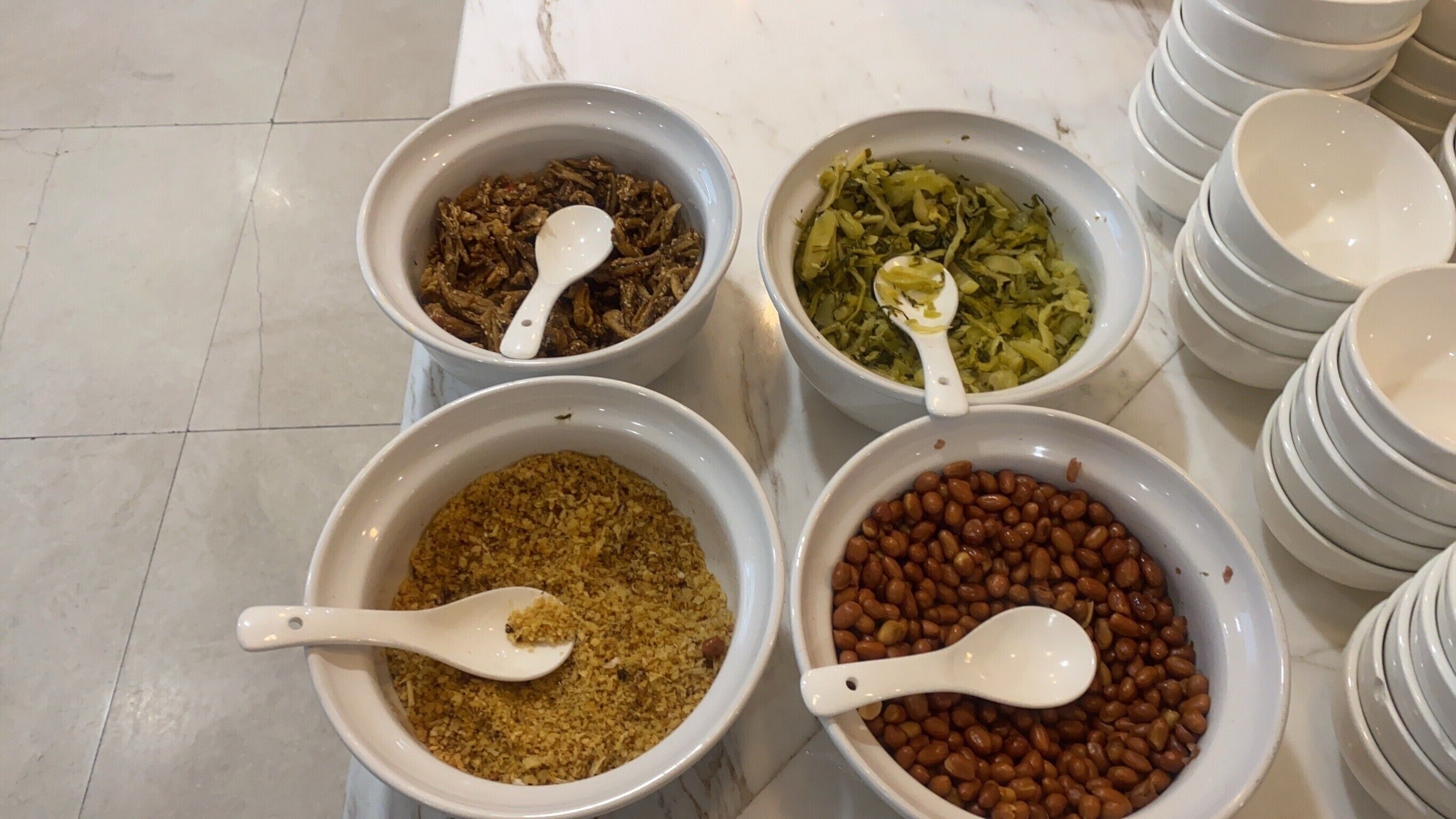 Four bowls of food items on a marble countertop.