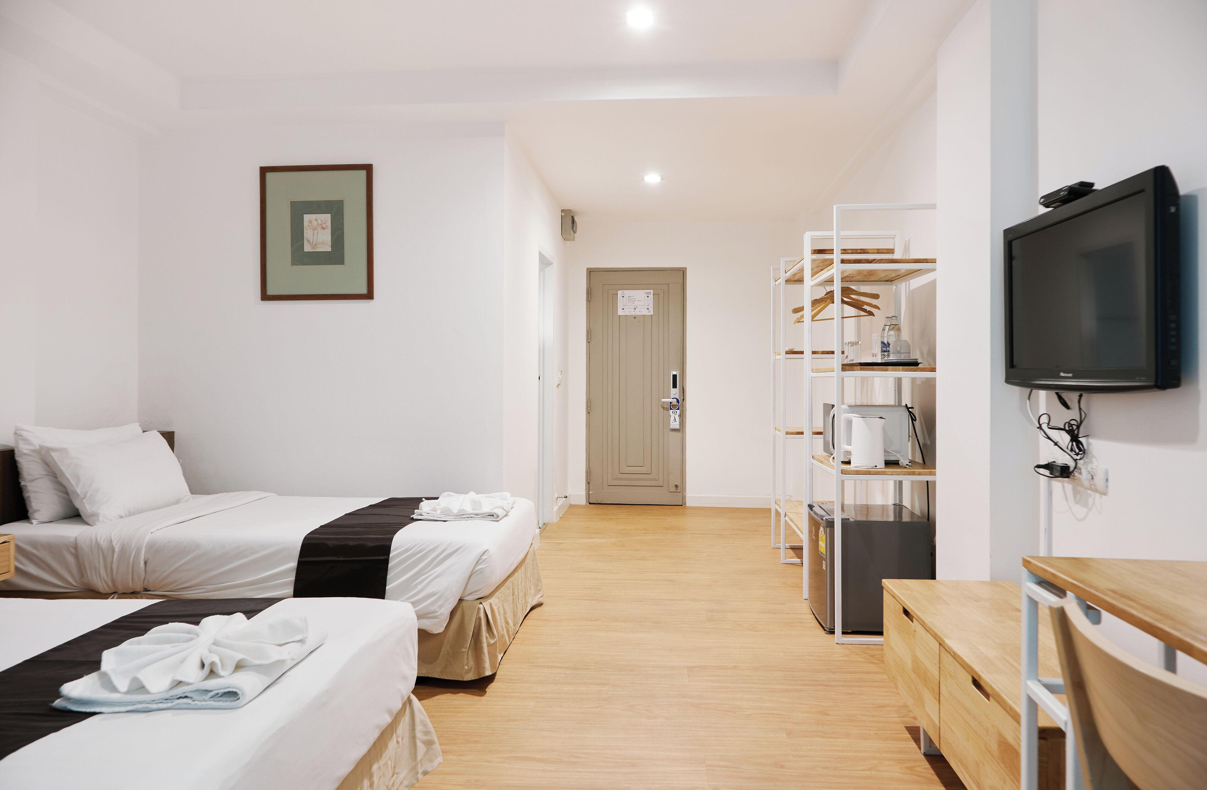 A hotel room with two beds, a TV, a mini-fridge, a microwave, and a wooden desk.