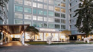 A modern hotel entrance with a covered walkway, a sign for 'The Platinum Suite', and two elephant statues. - Sunday Platinum Suites (Bangkok)