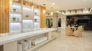A modern hotel lobby with a marble reception desk, wooden accents, and a seating area with beige chairs. - Sunday Platinum Suites (Bangkok)