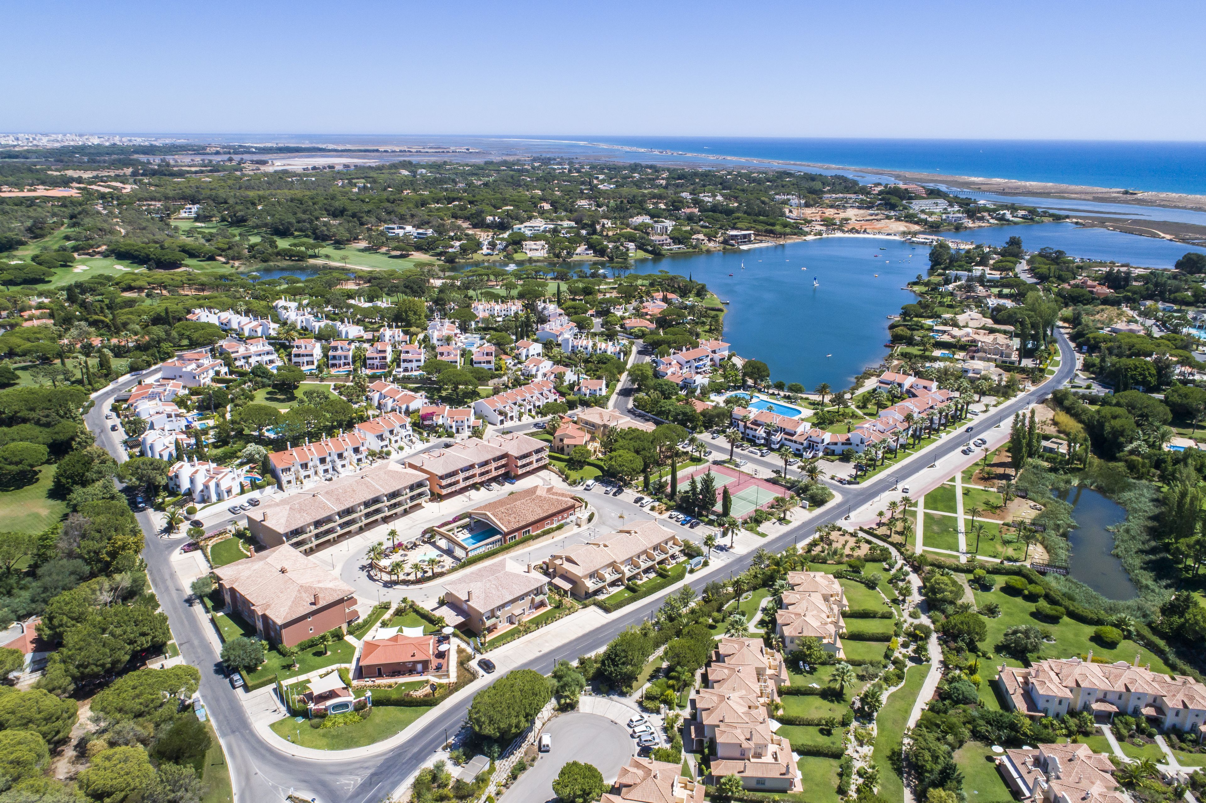 An aerial view of a coastal resort with multiple buildings, a marina, and a large body of water.