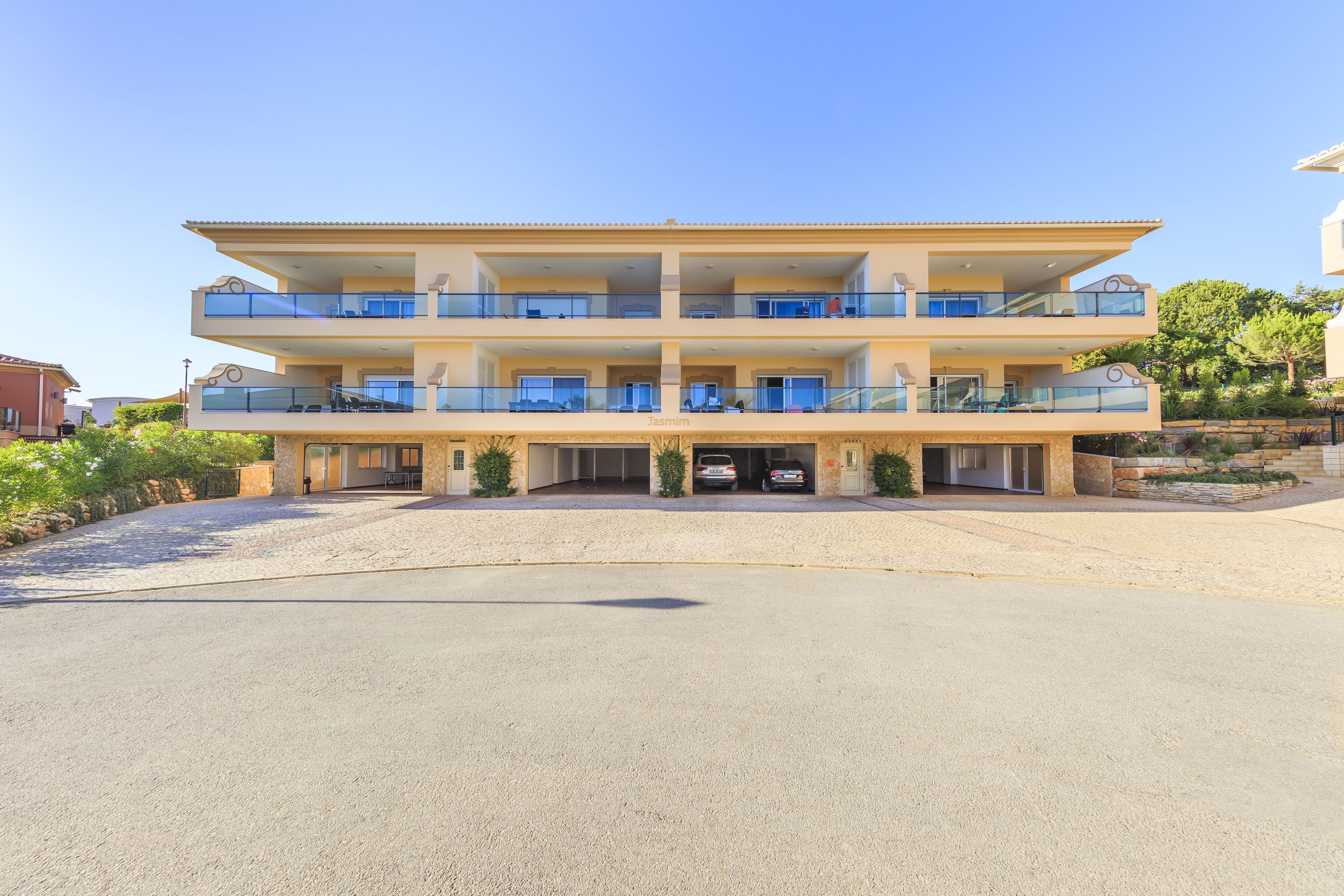 A multi-story hotel with balconies, a parking area, and a clear sky.