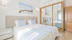 Una habitación de hotel con una cama grande, una mesita de noche, un armario y un cuadro en la pared.
