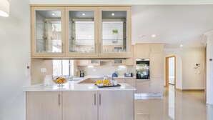 Una cocina moderna con armarios de madera clara, una isla central con productos para el desayuno y electrodomésticos integrados.