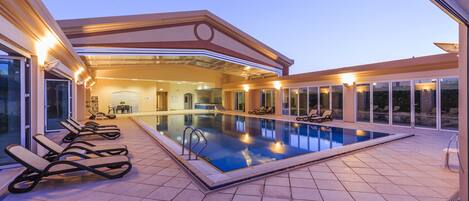 A swimming pool with lounge chairs and a covered area with a view of the interior.