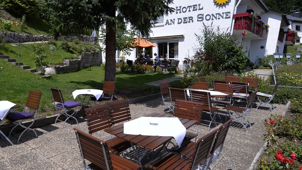 Un hotel llamado "Hotel Land der Sonne" con terraza y jardín.