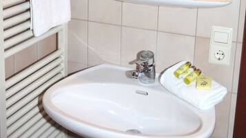 A bathroom with a white sink, towel rack, and a mirror.