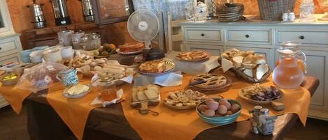 A buffet table with various food items and a fan.