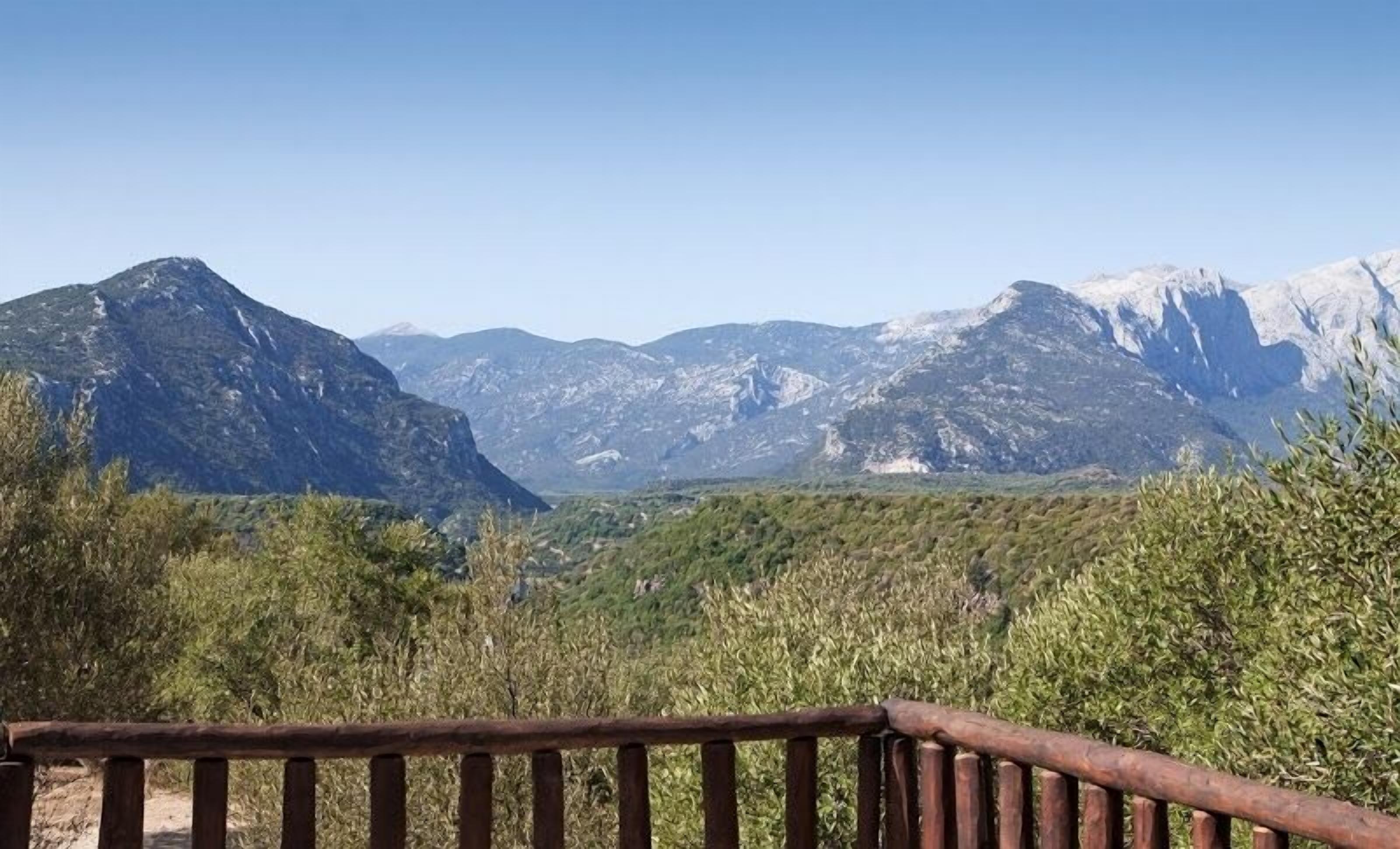 A mountainous landscape with a wooden fence in the foreground.