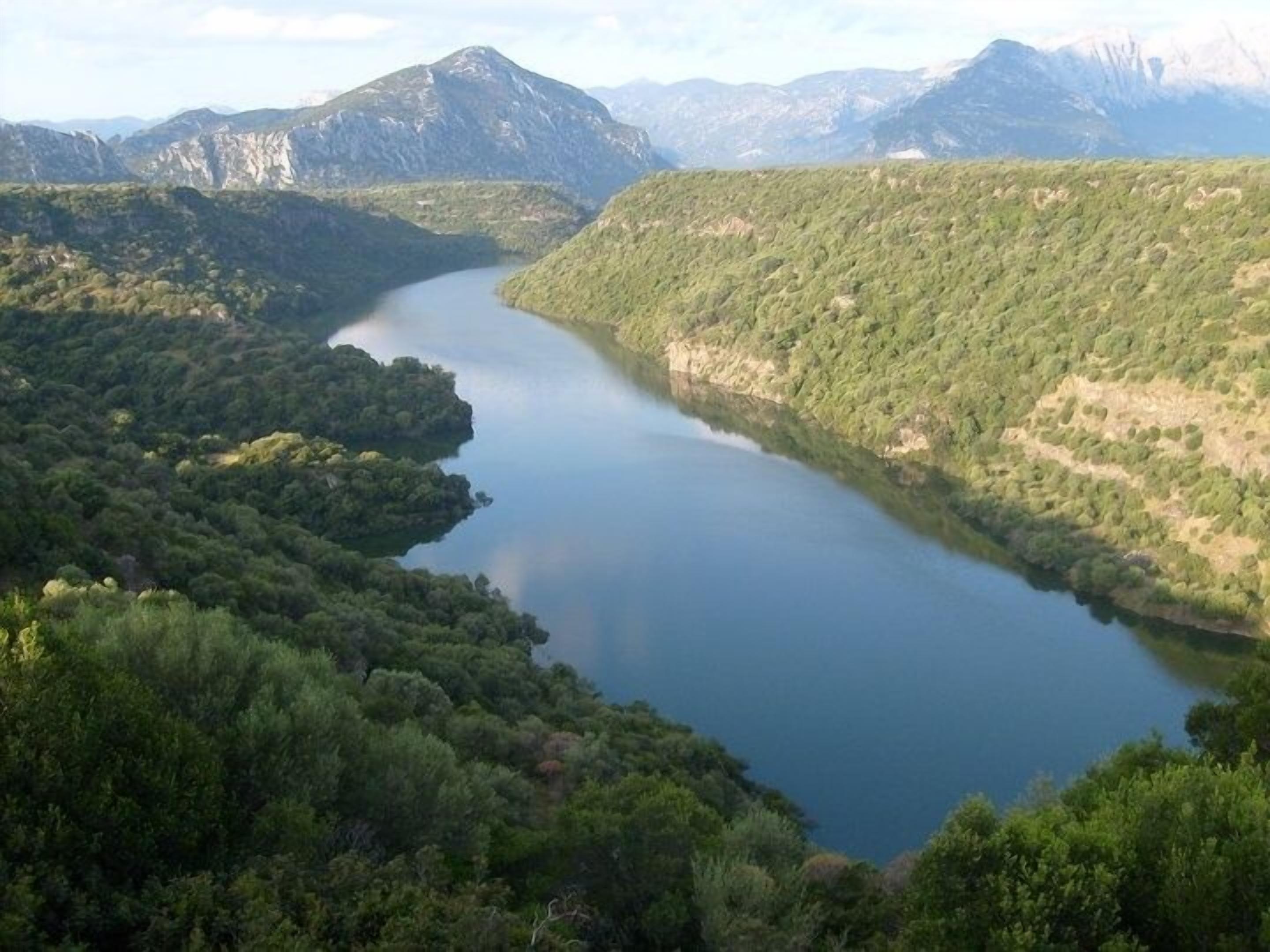 A lake surrounded by forested hills and mountains.