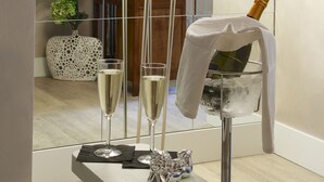 Une salle de bain moderne avec un grand lampadaire, deux coupes à champagne et une bouteille de champagne posée sur une serviette.
