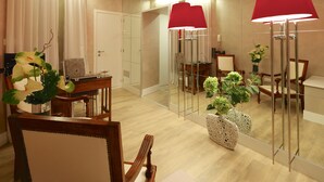 Une chambre d’hôtel moderne avec une table à manger en bois, des chaises, une lampe rouge et un miroir qui reflète la pièce.