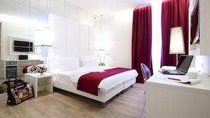 Une chambre d’hôtel moderne équipée d’un lit, d’un bureau et d’un téléviseur fixé au mur.