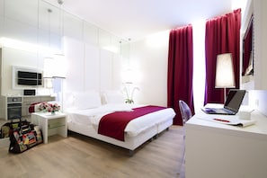 Quarto de hotel moderno com cama, escrivaninha e televisão na parede.