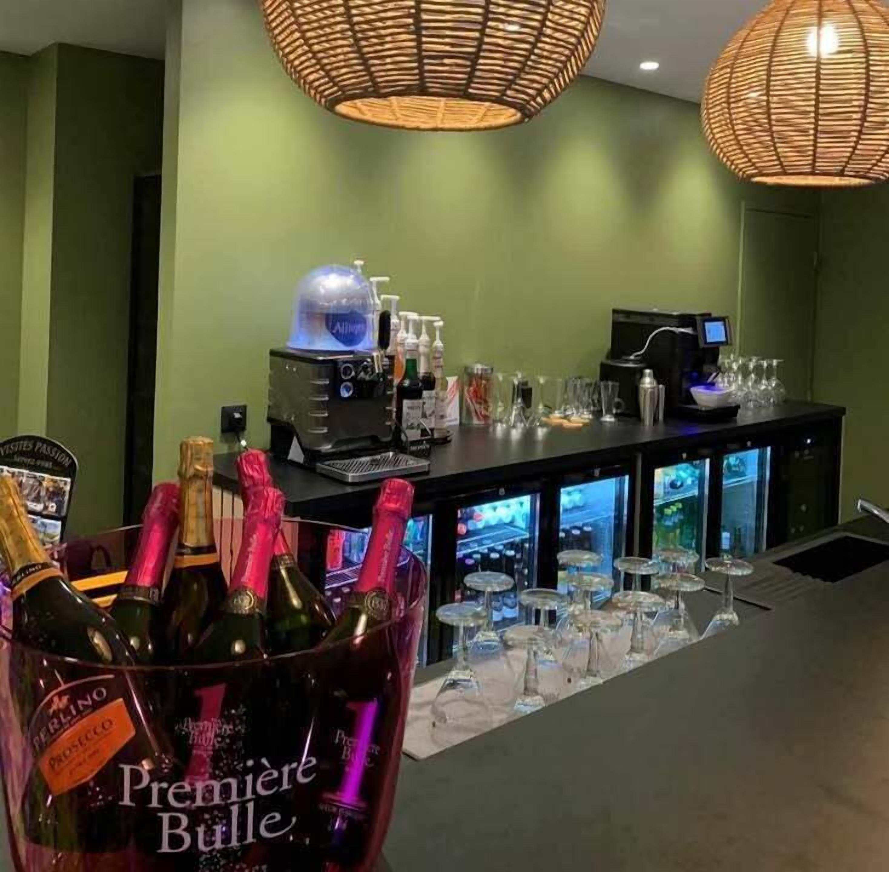 A bar area with bottles of champagne, a minibar, and a coffee machine.