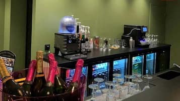 A bar area with bottles of champagne, a minibar, and a coffee machine.