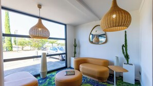 Une chambre moderne dotée d’une grande fenêtre, d’un canapé, d’une table basse et de deux lampes suspendues en osier.
