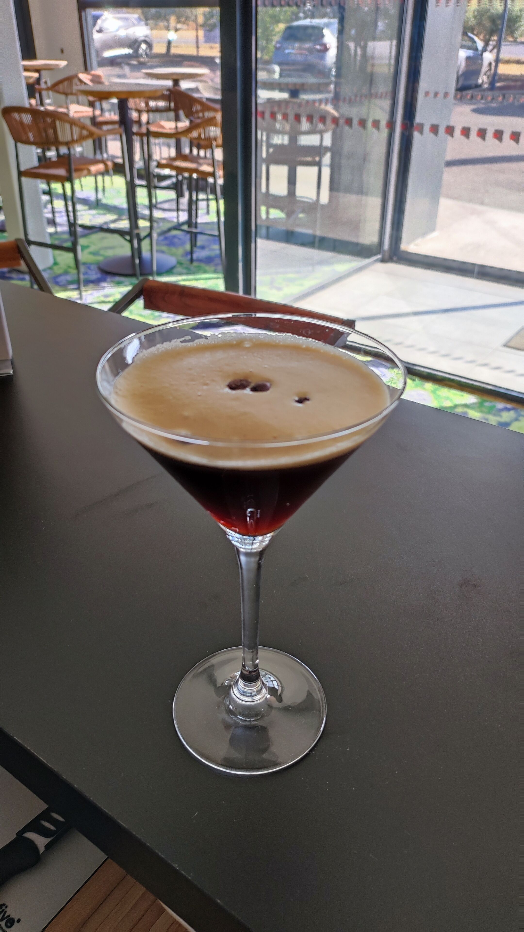 Una copa de martini con espuma sobre una superficie oscura.