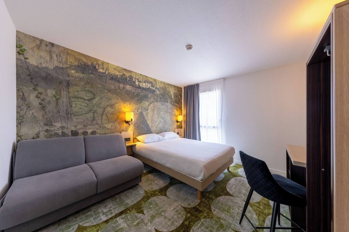 Une chambre d’hôtel comprenant un lit, un canapé, un bureau et une grande fresque murale.
