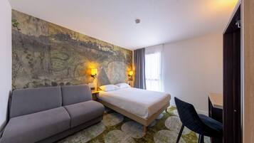 Habitación de hotel con cama, sofá, escritorio y un mural grande en la pared.