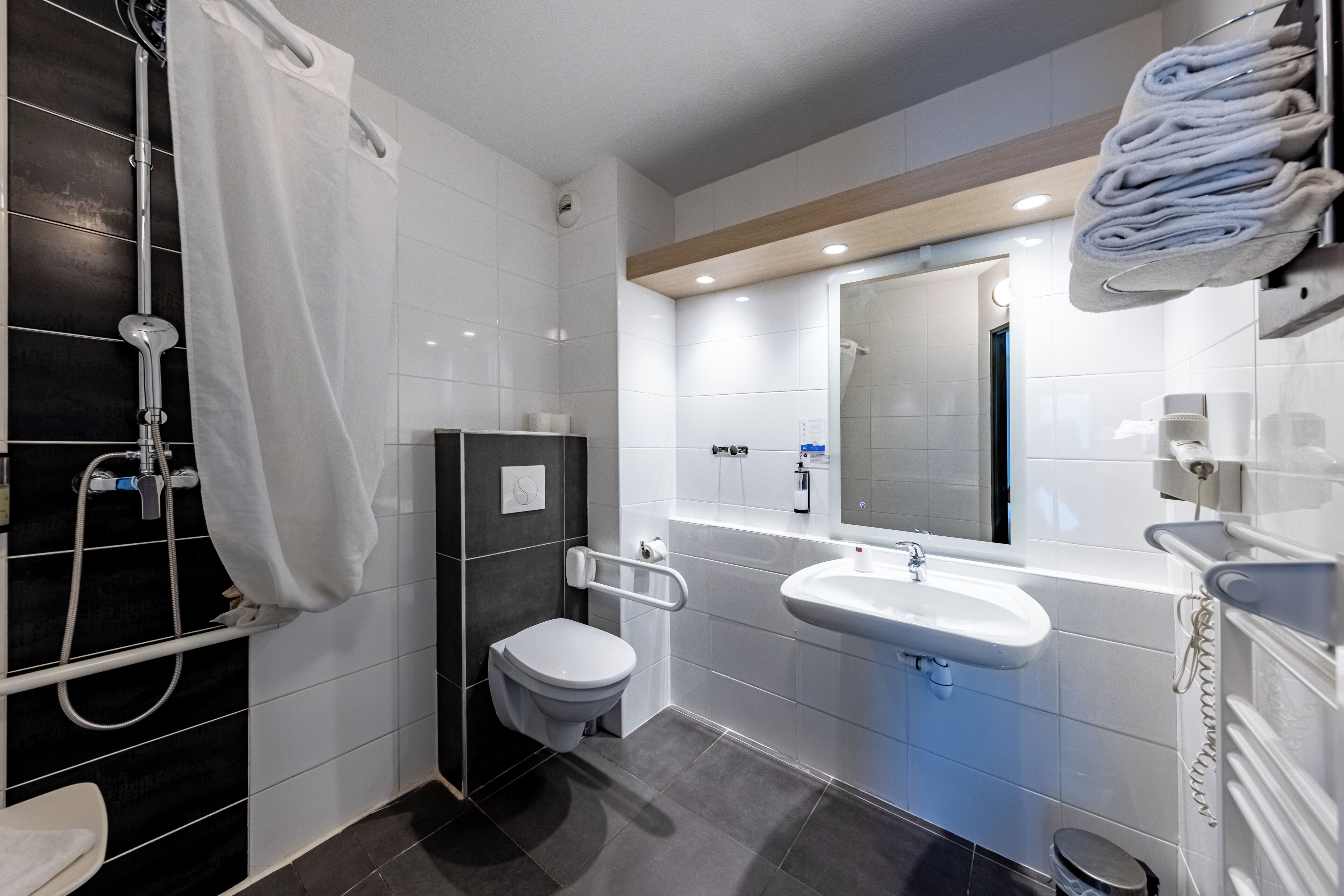 A modern bathroom with a shower, toilet, sink, and a towel rack.