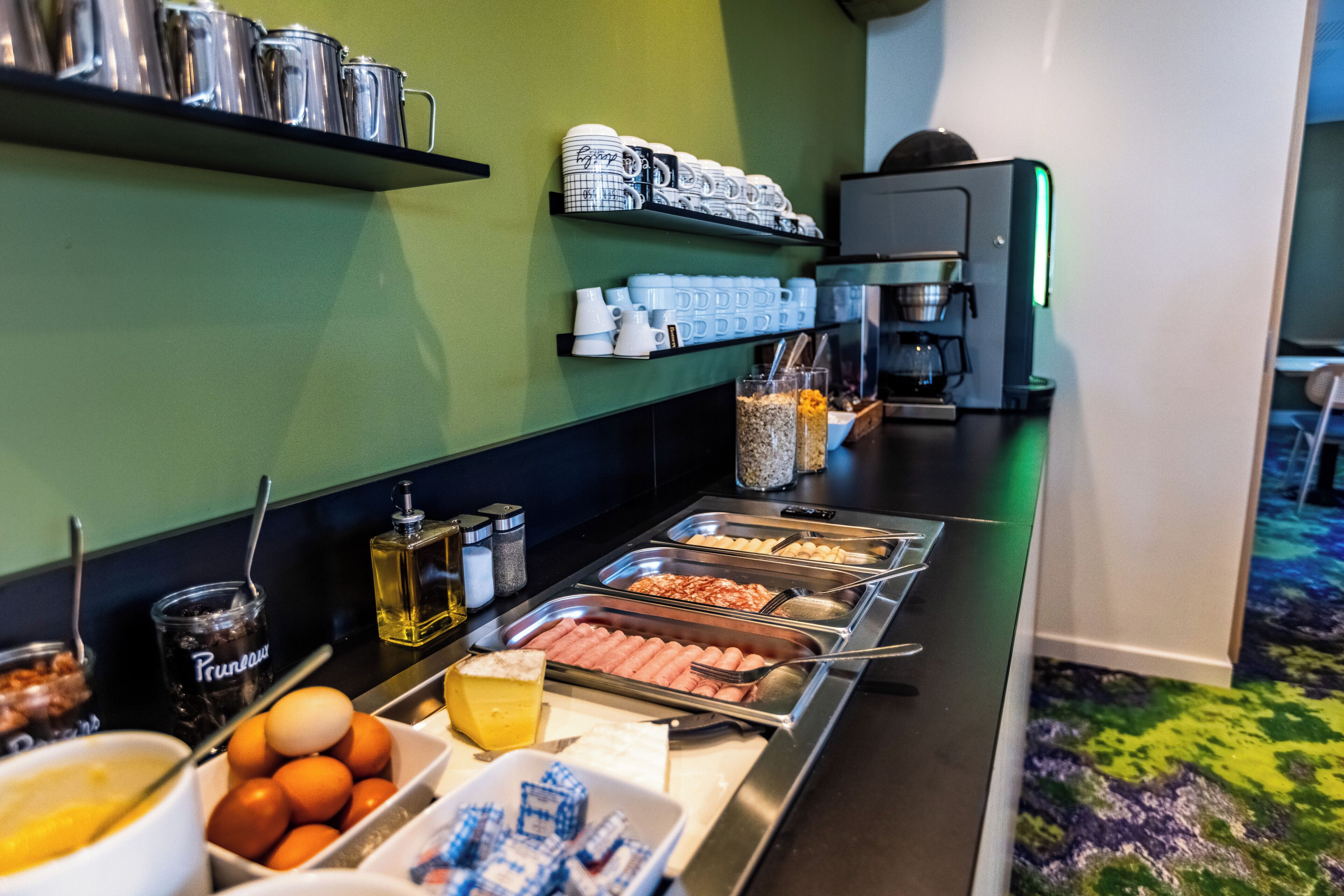 A buffet setup with various food items and beverages, including hot dogs, eggs, and coffee.