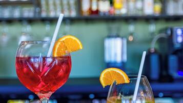 Deux cocktails sur le comptoir d’un bar, avec en arrière-plan, flou, des étagères remplies de bouteilles.