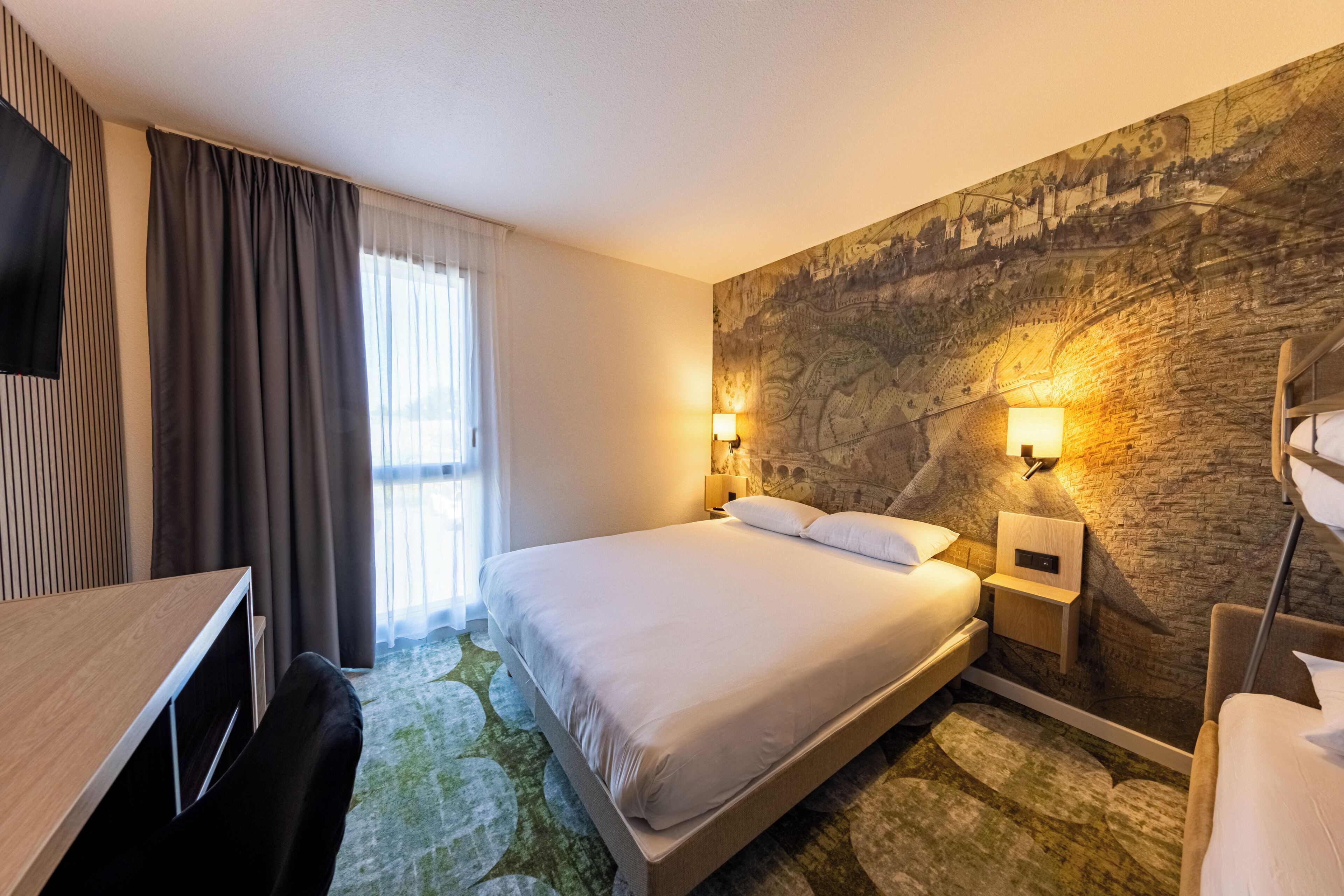 Ein Hotelzimmer mit einem großen Bett, einem Schreibtisch und einem Fernseher.